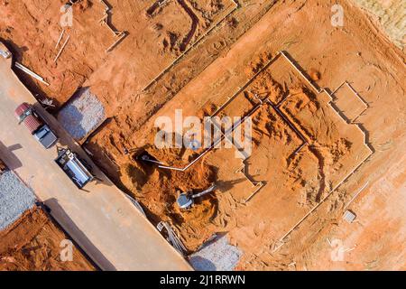 Luftaufnahme einer Planierraupe bei Neubauinstallation auf Wasserentwässerungssystem in neuem Fundament Stockfoto