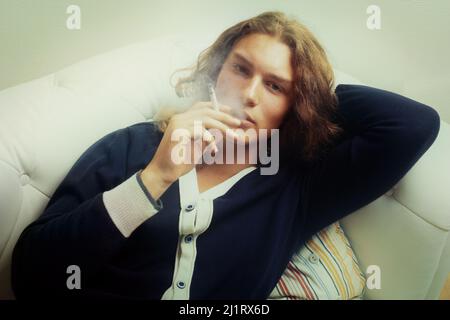 Schlechte Gewohnheiten sind schwer zu brechen. Porträt eines hübschen jungen Mannes, der eine Zigarette raucht. Stockfoto