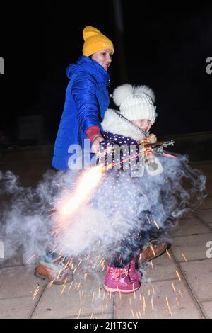 Vendrell, Spanien. 05. Januar 2022. Eine ukrainische Flüchtlingsmutter mit ihrer Tochter spielt mit einem Feuerwerkskörper in Vendrell. Die Vereinigung „DRAC de FOC El Cabrot de El Vendrell“ (Feuerdrache) handelt in einer pyrotechnischen Darstellung in Solidarität und Unterstützung für Menschen ukrainischer Nationalität, die aufgrund der Invasion Russlands in der Ukraine in Hotels und kommunalen Hostels in der Stadt Vendrell Flüchtlinge sind, Die Aufführung von Feuerparaden ist eine katalanische Tradition, die jedes Jahr in Städten und Gemeinden stattfindet. Kredit: SOPA Images Limited/Alamy Live Nachrichten Stockfoto