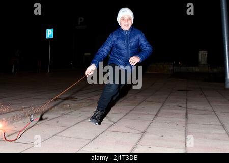 Vendrell, Spanien. 05. Januar 2022. Ein ukrainischer Flüchtlingsjunge spielt in Vendrell mit einem Feuerstock. Die Vereinigung „DRAC de FOC El Cabrot de El Vendrell“ (Feuerdrache) handelt in einer pyrotechnischen Darstellung in Solidarität und Unterstützung für Menschen ukrainischer Nationalität, die aufgrund der Invasion Russlands in der Ukraine in Hotels und kommunalen Hostels in der Stadt Vendrell Flüchtlinge sind, Die Aufführung von Feuerparaden ist eine katalanische Tradition, die jedes Jahr in Städten und Gemeinden stattfindet. Kredit: SOPA Images Limited/Alamy Live Nachrichten Stockfoto