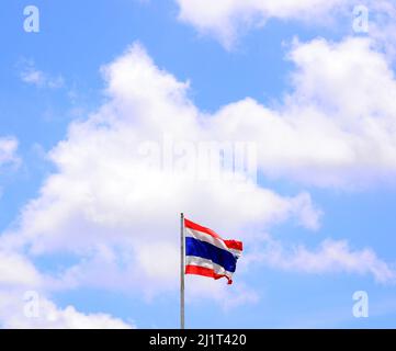 Eine thailändische Flagge flattert im Wind gegen einen wolkigen blauen Himmel in Thailand, Asien Stockfoto