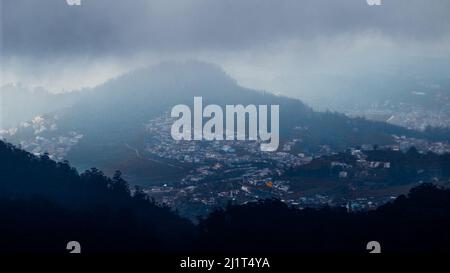 Eine schöne Aufnahme von Ooty Dorf Blick von Doddabetta Spitze unter einem bewölkten Himmel in Tamil Nadu, Indien Stockfoto