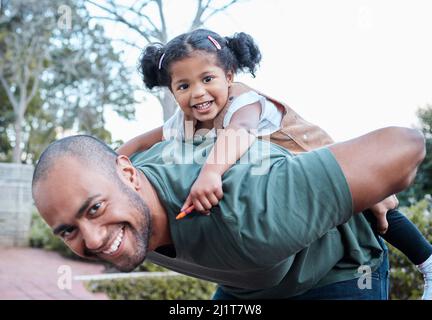 Waren immer in der Stimmung für etwas Spaß. Aufnahme eines Mannes, der seine Tochter auf dem Rücken trägt, während er draußen steht. Stockfoto