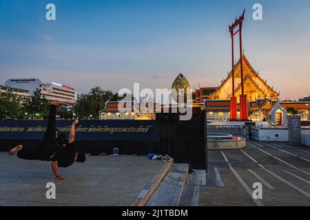 Ein Mann sah, wie er vor dem Giant Swing in Bangkok Straßentanz übte. Rattanakosin Island, das Innere Bangkoks, ist der Kern der historischen und kulturellen Zone Bangkoks. Dieser Ort ist auch bekannt als eine alte Stadt wegen des Alters der Zone, dass mehr als 100 Jahre des Bestehens. Nicht nur Palast, Tempel und Wahrzeichen dieser Zone umfassen das Leben und die Aktivitäten der Menschen, die rund um die heilige Gegend von Bangkok leben. Stockfoto