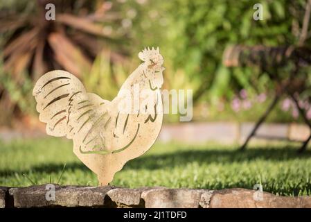 Ein Stahl- oder Eisenprofil eines Hahns als Gartenschmuck vor einem gemähten grünen Rasen in einem Hinterhof in Sydney, Australien Stockfoto