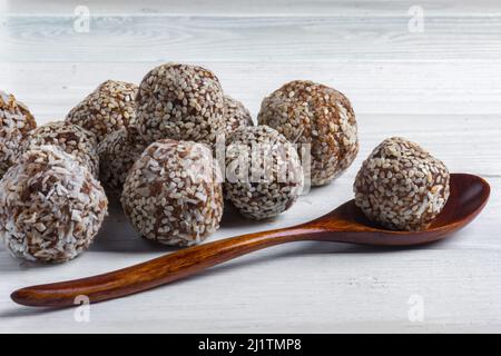 Nahaufnahme von No Bake Energy Balls auf weißem Hintergrund mit Holzlöffel. Weichfokus Stockfoto