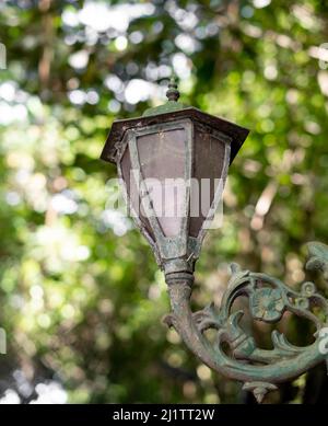 Patina Finish auf Lampe in Bali, indonesische Straße, Hintergrund ist verschwommen Blätter von den Bäumen Stockfoto