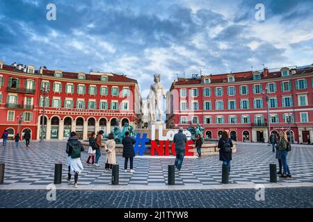 Nizza, Frankreich - 10. April 2018: Menschen auf dem Place Massena mit dem Sonnenbrunnen (Fontaine du Soleil) und der Apollo-Statue. Stockfoto