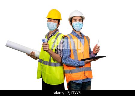 Zwei junge asiatische Ingenieure tragen eine OP-Maske mit Tablette und Blaupause isoliert auf weißem Hintergrund. Neues normales Konzept. (Mit Beschneidungspfad) Stockfoto