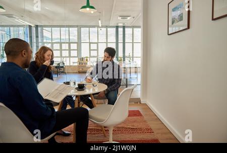 Geschäftsleute, die sich während einer zwanglosen Besprechung in einem Büro unterhalten Stockfoto