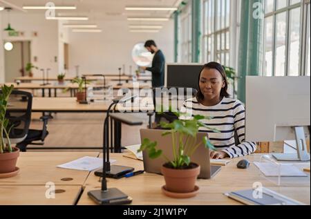 Fokussierte junge afrikanische Geschäftsfrau, die an ihrem Schreibtisch in einem Büro arbeitet Stockfoto