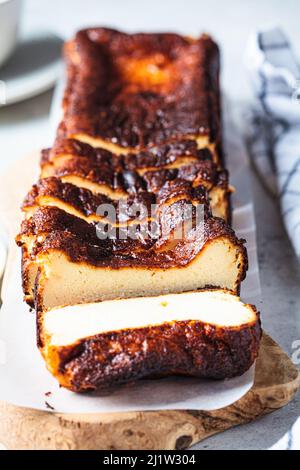 Hausgemachter rechteckiger San Sebastian verbrannte Käsekuchen auf Holzbrett zum Frühstück, Nahaufnahme. Stockfoto