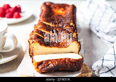 Hausgemachter rechteckiger San Sebastian verbrannte Käsekuchen auf Holzbrett zum Frühstück, Nahaufnahme. Stockfoto