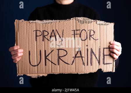 Frau hält ein Banner mit Anti-Kriegs-Botschaft. Protest gegen die russische Intervention in der Ukraine, Aktivismus und Menschenrechtsbewegung. Konzept der Standi Stockfoto