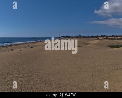 Blick über den überfüllten Strand Playa de Maspalomas mit beliebten Sanddünen und Leuchtturm im Süden der Insel Gran Canaria, Spanien an der Atlantikküste. Stockfoto