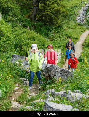 Frau beim Wandern mit einer Gruppe von Kindern in der Alpenregion um Warth am Arlberg Stockfoto