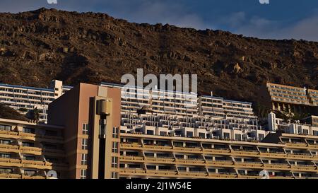 Blick auf große mehrstöckige Hotel- und Apartmentgebäude an einem Hang unter Felsen im Ferienort Taurito an der Südküste von Gran Canaria, Spanien. Stockfoto