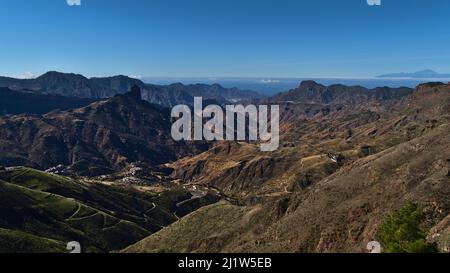 Atemberaubender Panoramablick auf die zentralen Berge von Gran Canaria, Spanien von Cruz de Tejeda aus mit dem berühmten Felsen Roque Bentayga und der Insel Teneriffa. Stockfoto