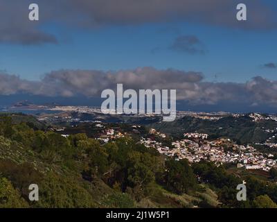 Blick über den Nordosten der Insel Gran Canaria, Spanien mit dem kleinen Dorf Teror, umgeben von grünen Hügeln und der Hauptstadt Las Palmas im Hintergrund. Stockfoto