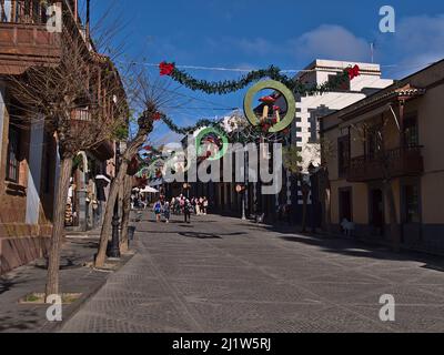 Touristen zu Fuß durch Fußgängerzone im historischen Zentrum der Altstadt von Teror auf Gran Canaria, Kanarische Inseln, Spanien in der Wintersaison mit Geschäften. Stockfoto