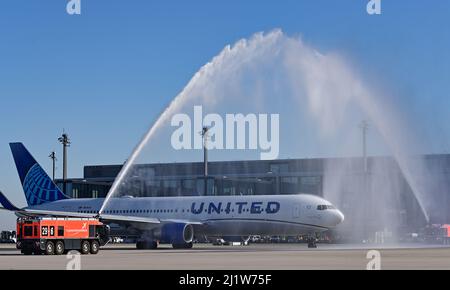 Berlin, Deutschland. 28. März 2022, Brandenburg, Schönefeld: Ein Passagierflugzeug der United Airlines wird von der Flughafenfeuerwehr am Flughafen BER der Hauptstadt für seinen ersten Flug vom BER zum New Yorker Flughafen Newark abgeflogen. Berliner und Brandenburger müssen auf Flügen zur US-Ostküste nicht mehr unbedingt ihre Flugzeuge wechseln. Ab Montag verbindet United Airlines Schönefeld täglich direkt mit dem New Yorker Flughafen Newark. Es ist die erste Fernverbindung vom BER in die USA. Quelle: dpa picture Alliance/Alamy Live News Stockfoto