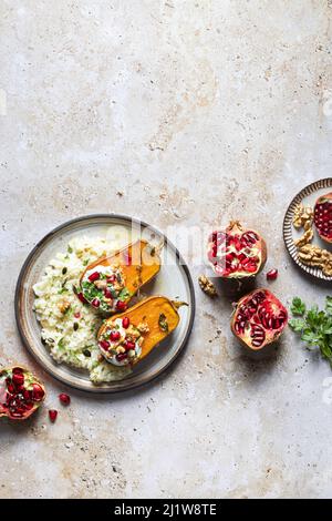 Draufsicht Zusammensetzung des Tellers mit leckerem Reis und geröstetem Kürbis, serviert mit Kräutern und Granatapfel in der Nähe von Nüssen Stockfoto