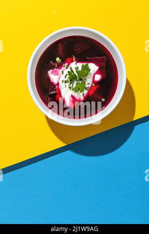 Von oben Schale mit leckeren Borscht mit Rote Bete auf dem Hintergrund der Farben der ukrainischen Flagge gemacht Stockfoto