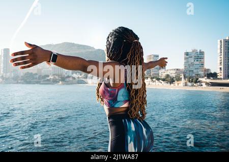 Fröhlicher männlicher Tourist, der an sonnigen Sommertagen barfuß auf einer hölzernen Promenade am Sandstrand läuft Stockfoto