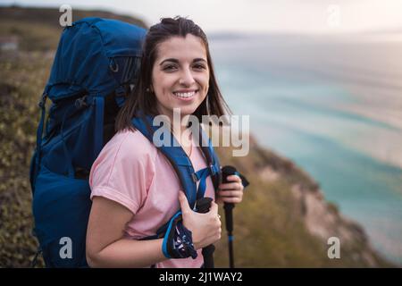 Von unten selbstbewusste junge bärtige afroamerikanische Männer Millennial mit trendigen Broten in zwanglosem Outfit, die auf der Straße in der Nähe eines modernen Gebäudes und stehen Stockfoto