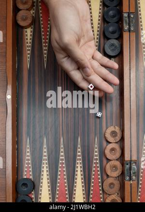 Nahaufnahme Frau Hand hält Backgammon Würfel und spielt Backgammon draußen. Der Fokus liegt auf ihrer Hand. Stockfoto