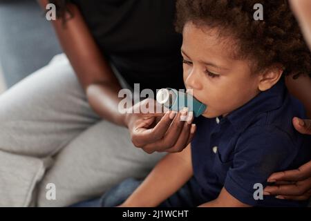 Mutter hilft dem kleinen Sohn, Asthma-Inhalator gegen allergische Attacken zu verwenden Stockfoto