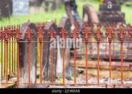 Eine Seite auf dem Bild von geschnitzten Steingrabsteinen umgeben von einem niedrigen gusseisernen Zaun auf einem alten Friedhof oder Friedhof in Sydney, New South Wales, Australien Stockfoto