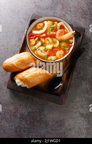 Caldeirada de frutos do mar Eintopf mit Gemüse und Meeresfrüchten in der Schüssel auf dem Holztablett. Vertikale Ansicht von oben Stockfoto
