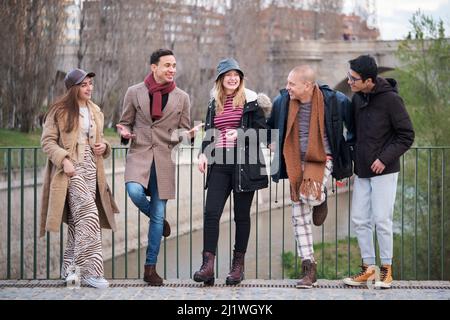 Eine Gruppe von Freunden unterschiedlichen Alters und Ethnien redet und lacht im Freien. Stockfoto