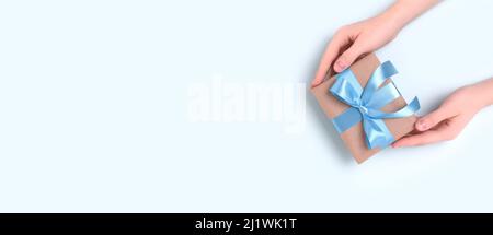 Weibliche Hände halten Geschenkbox mit blauem Band gebunden. Stockfoto