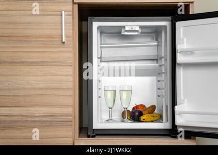 Zwei Gläser Champagner oder Sekt und reife Früchte im geöffneten Kühlschrank Stockfoto
