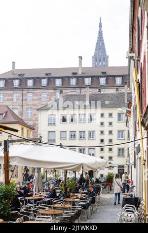 Straßburg, Frankreich - Mar 21, 2015: Place du Marche Gayot mit Menschen entspannen outisde die Terasse Bars mit großen Turm von Notre-Dame de Strasbour Kathedrale Stockfoto