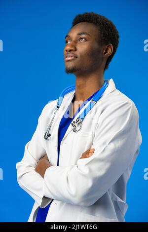 Selbstbewusster schwarzer Arzt posiert über blauem Studiohintergrund. Stockfoto