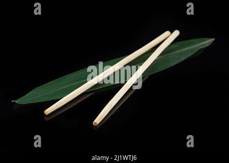 Sushi-Sticks auf einem Bananenblatt auf schwarzem Hintergrund mit Spiegelung. Sushi-Menü. Japanische Küche, Restaurant. Asiatische Küche Stockfoto