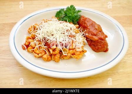 Schale und Elbow Pasta mit Sauce und Käse und einer Wurst auf der Seite Stockfoto