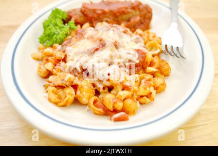 Schale und Elbow Pasta mit Sauce und Käse und einer Wurst auf der Seite Stockfoto