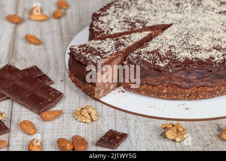 Schokoladenkuchen mit einem geschnittenen Stück auf grauem Hintergrund, Nahaufnahme Stockfoto