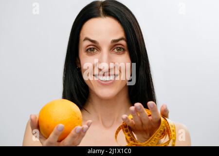 Die Hand der Frau hält ein zentimeterlanges Band und Zitronenfrüchte. Das Konzept eines gesunden Lebensstils, natürliche Bio-Lebensmittel-Konzept. Stockfoto