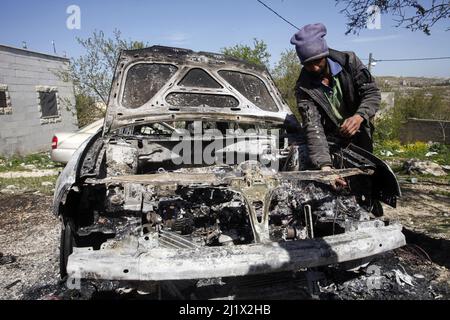 Nablus, Palästina. 28. März 2022. Ein Palästinenser inspiziert sein verbranntes Auto, nachdem israelische Siedler vier palästinensische Autos angezündet, ihr Eigentum zerstört und ihre Häuser im Dorf Jalud südlich von Nablus im besetzten Westjordanland zerstört haben. Viele der israelischen Siedler randalierten in den palästinensischen Dörfern in der Nähe der Außenposten nach einem Schussangriff von Palästinensern im besetzten Hadera-Gebiet im Jahr 1948. Kredit: SOPA Images Limited/Alamy Live Nachrichten Stockfoto