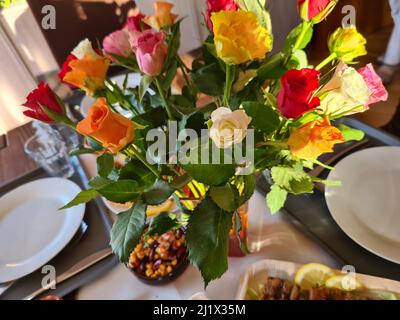 Ein Strauß Rosen in einer Vase auf einem Nachttisch Stockfoto