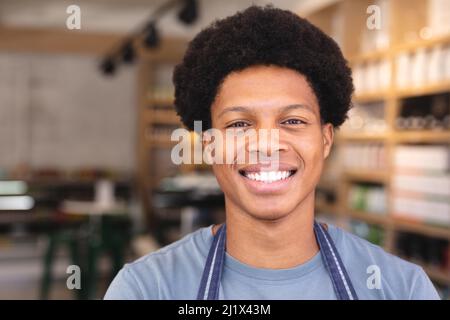 Porträt eines lächelnden jungen afroamerikanischen Mitarbeiters mit Afro-Frisur im Café. Unverfälscht, Café-Kultur, Menschen und Beruf Konzept. Stockfoto