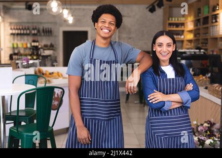 Portrait von selbstbewussten multirassischen Baristas mit Schürzen im Coffee Shop. Unverändertes Café-Kultur-, Menschen- und Besatzungskonzept. Stockfoto