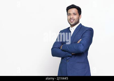 Junger hispanischer Geschäftsmann mit überkreuzten Armen lächelnd. Stockfoto