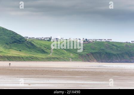 Bei Ebbe bietet sich ein weitläufiger Blick auf den riesigen Sandstrand in der Rhossili Bay. In der Ferne liegt Rhossili Down und das Clifftop Dorf Rhossili. Stockfoto