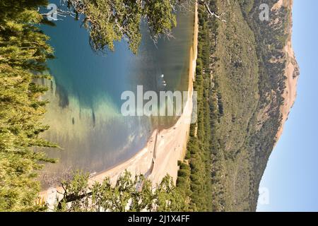Eine vertikale Aufnahme des Strandes am Moquehue-See im Hintergrund riesiger grüner Berge Stockfoto